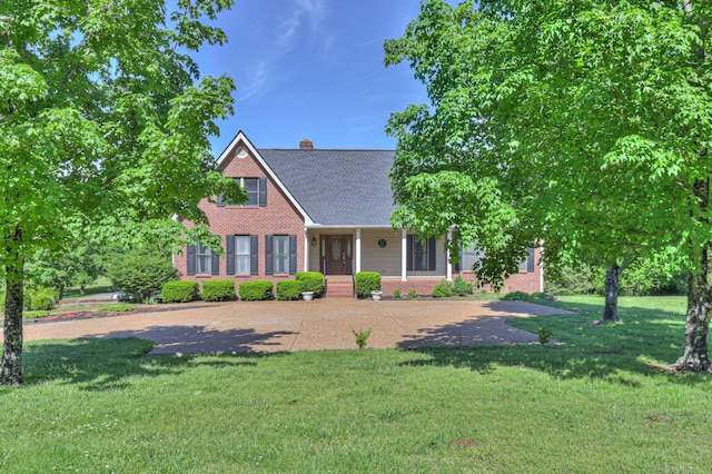 view of front facade with brick siding, a chimney, a front yard, and roof with shingles