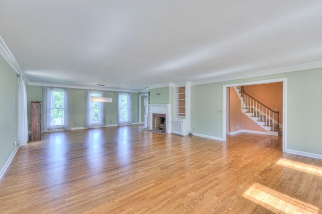 unfurnished living room with ornamental molding, a fireplace, light wood-type flooring, and baseboards