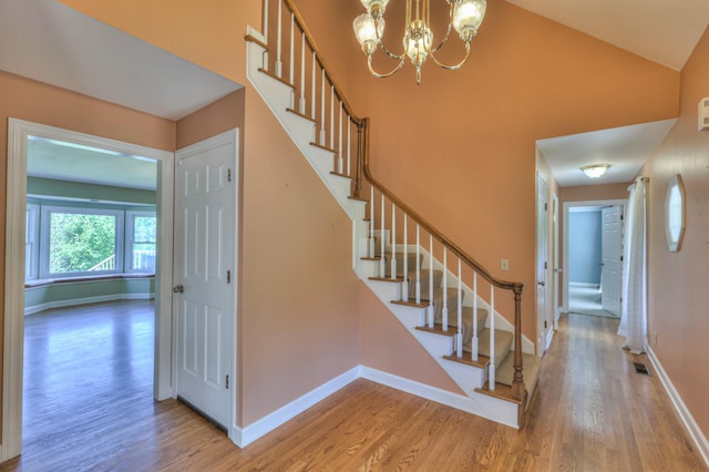 stairs featuring wood finished floors, a chandelier, and baseboards