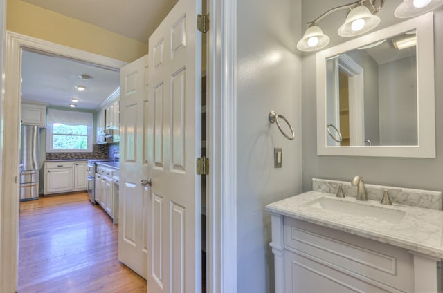 bathroom featuring wood finished floors, vanity, and decorative backsplash