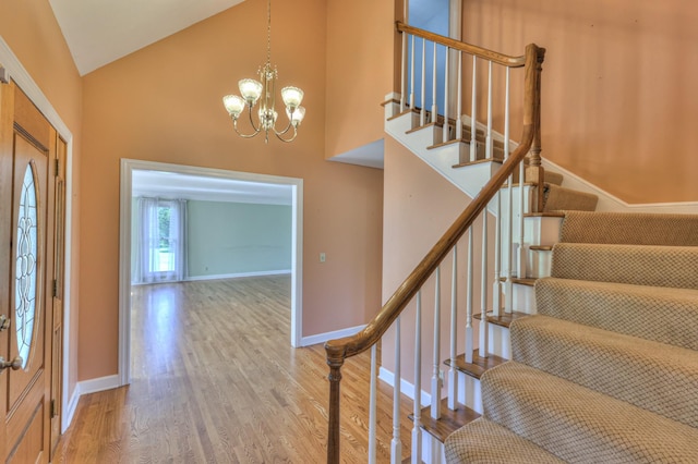 entryway featuring high vaulted ceiling, wood finished floors, stairs, a chandelier, and baseboards