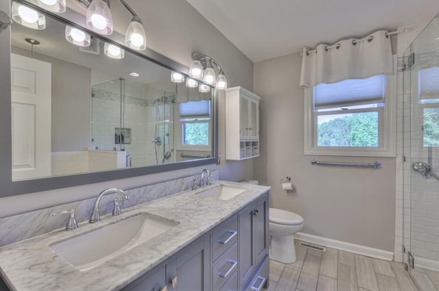 bathroom featuring a shower stall, baseboards, double vanity, toilet, and wood tiled floors