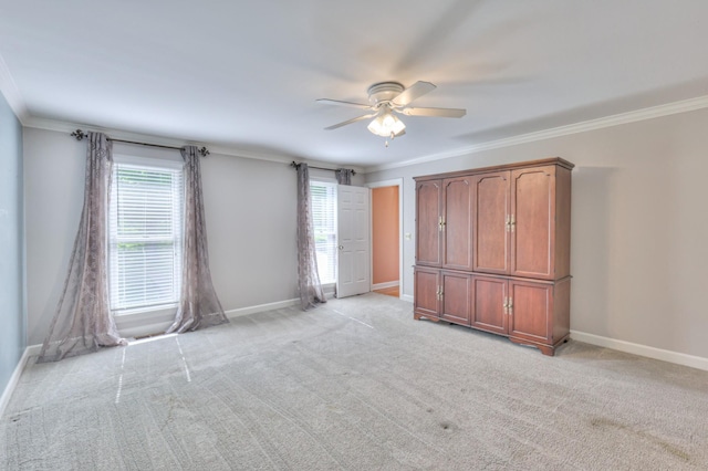 unfurnished bedroom featuring baseboards, multiple windows, ornamental molding, light carpet, and a ceiling fan