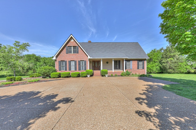 view of front of home with brick siding, a porch, a front lawn, and roof with shingles