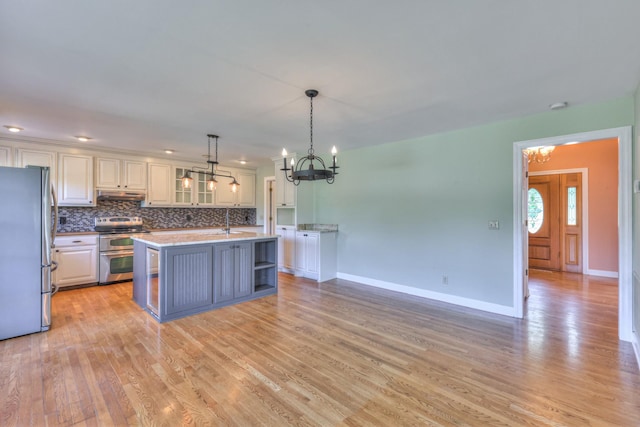kitchen with stainless steel appliances, a chandelier, under cabinet range hood, and light wood-type flooring