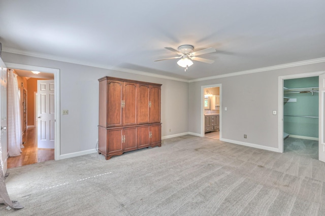 unfurnished bedroom featuring light colored carpet, ornamental molding, baseboards, connected bathroom, and a spacious closet