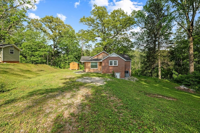 view of grassy yard featuring driveway, an attached garage, a storage shed, and an outbuilding