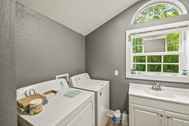 washroom featuring a textured wall, independent washer and dryer, and cabinet space