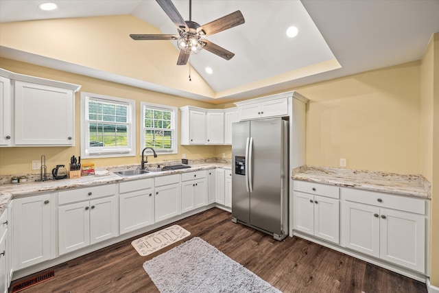 kitchen featuring stainless steel fridge, a sink, vaulted ceiling, recessed lighting, and white cabinetry