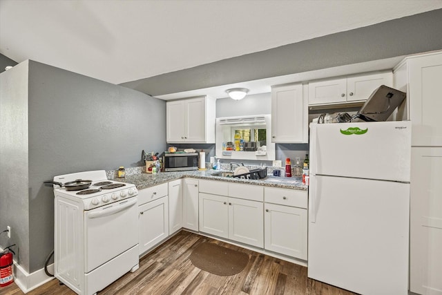 kitchen featuring white appliances, wood finished floors, white cabinets, a sink, and a textured wall
