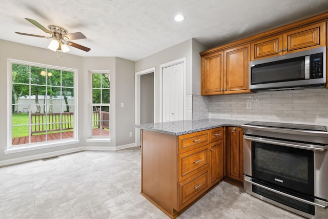 2907 York Rd, Pleasant View, TN 37146 - kitchen featuring appliances with stainless steel finishes, brown cabinetry, ceiling fan, tasteful backsplash, and light stone countertops