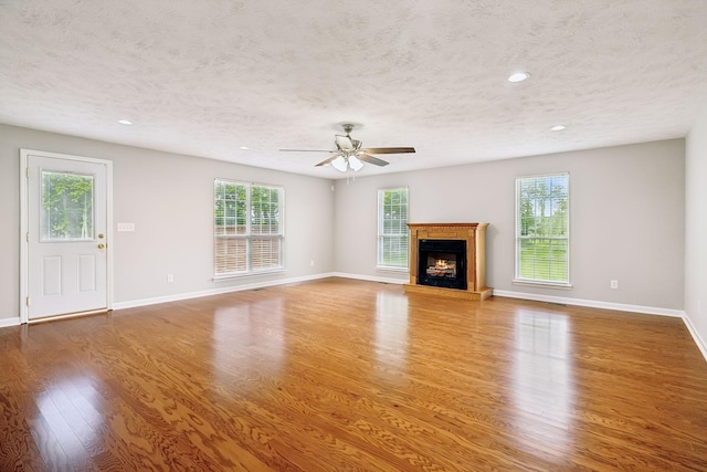 2907 York Rd, Pleasant View, TN 37146 - unfurnished living room with a textured ceiling, wood finished floors, healthy amount of natural light, baseboards, and a lit fireplace