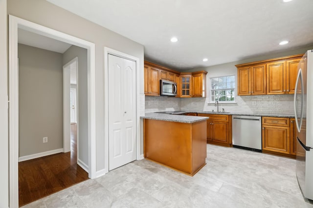2907 York Rd, Pleasant View, TN 37146 - kitchen with appliances with stainless steel finishes, brown cabinetry, a sink, tasteful backsplash, and light stone countertops