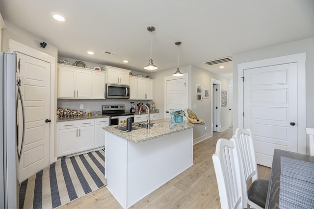kitchen featuring stainless steel appliances, a sink, light wood finished floors, white cabinetry, and recessed lighting