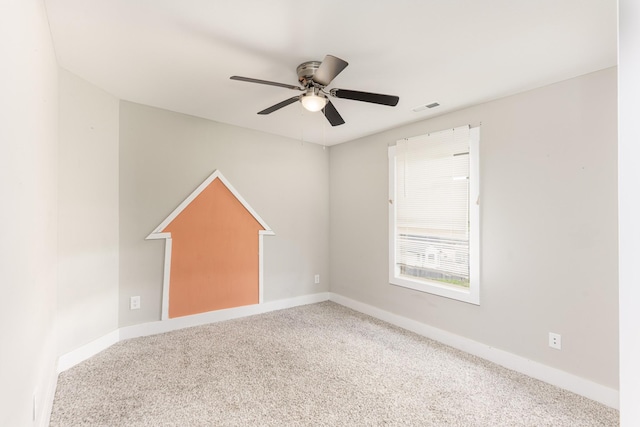carpeted spare room featuring a ceiling fan and baseboards