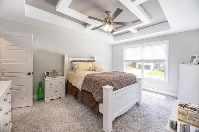 bedroom with a raised ceiling, light colored carpet, a ceiling fan, and baseboards