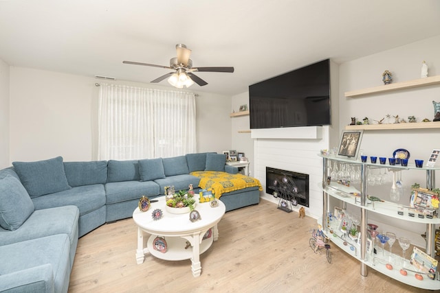 living room featuring wood finished floors, ceiling fan, and a glass covered fireplace
