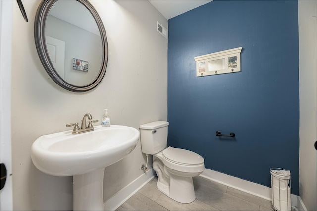 bathroom with baseboards, tile patterned floors, toilet, and a sink