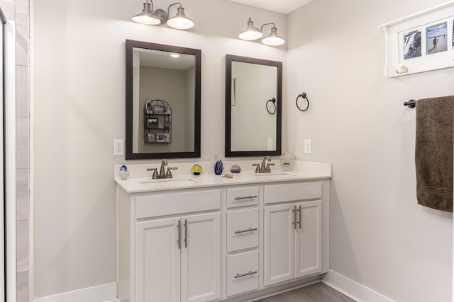 full bathroom featuring baseboards and double vanity