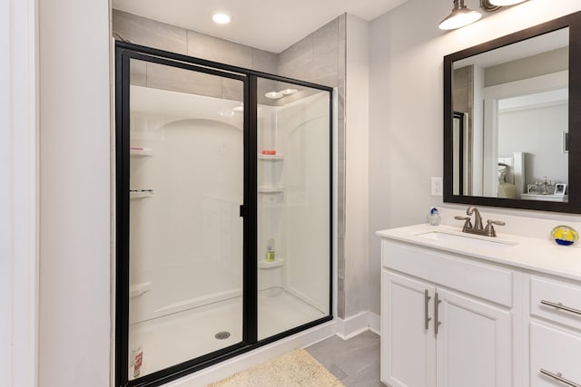 bathroom with a shower stall, vanity, and baseboards