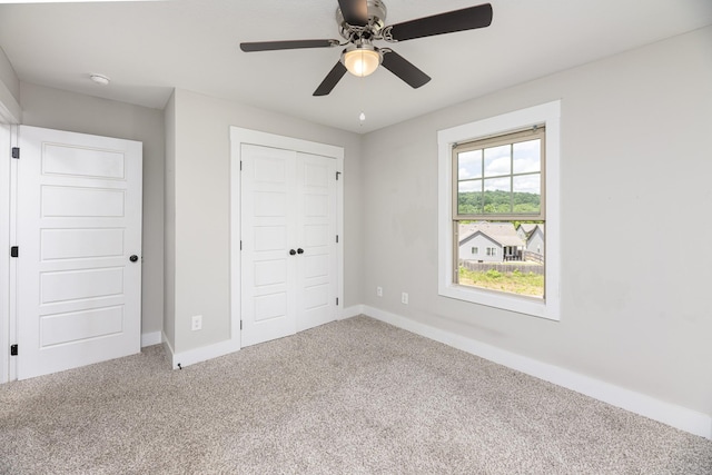 unfurnished bedroom with carpet floors, baseboards, a closet, and a ceiling fan