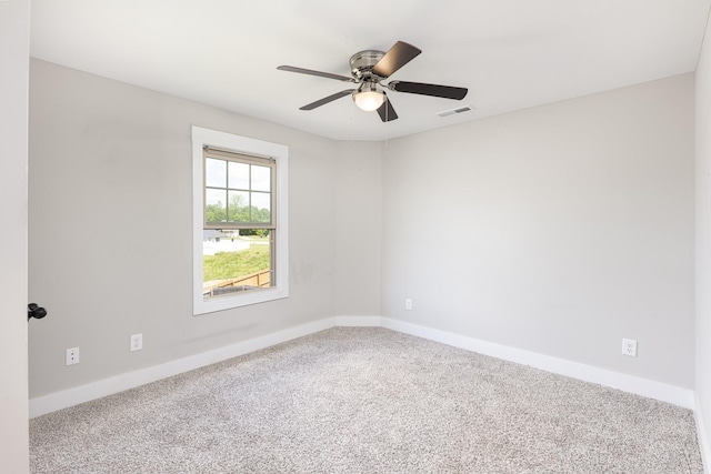 carpeted spare room featuring a ceiling fan and baseboards