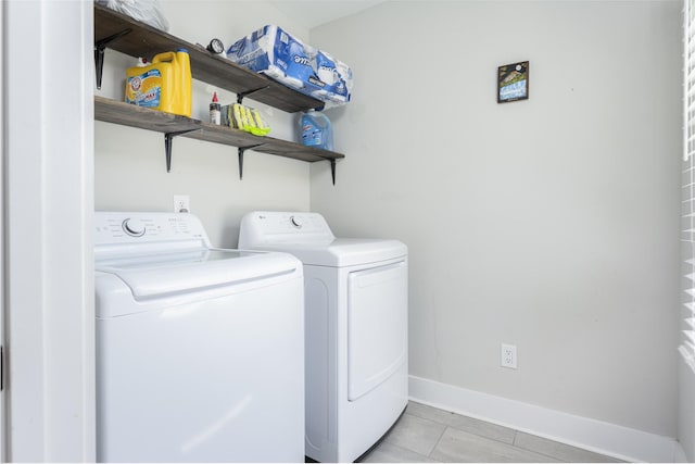 washroom featuring washer and clothes dryer, baseboards, and light tile patterned floors