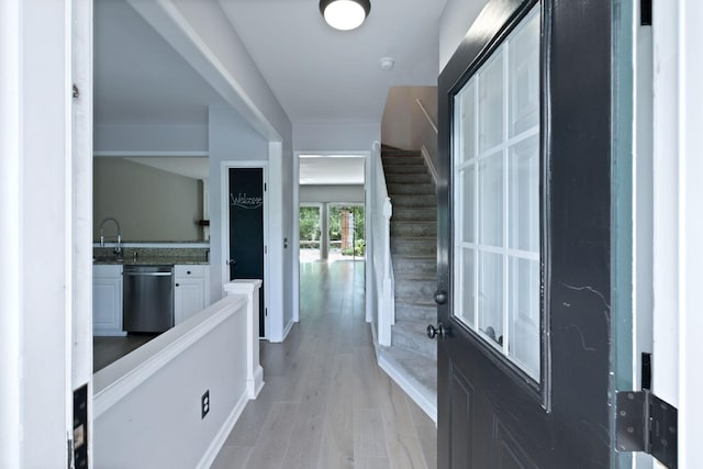 corridor with light wood-style flooring and a sink