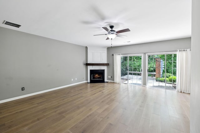 unfurnished living room with ceiling fan, baseboards, wood finished floors, and a fireplace