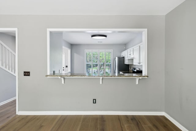 kitchen featuring freestanding refrigerator, dark wood-style floors, baseboards, and light stone countertops