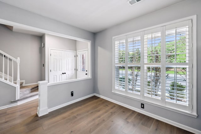 spare room with healthy amount of natural light, dark wood-style floors, baseboards, and stairs