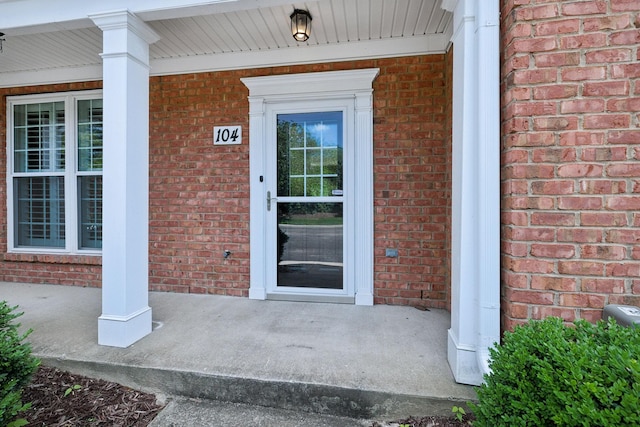 property entrance with covered porch and brick siding
