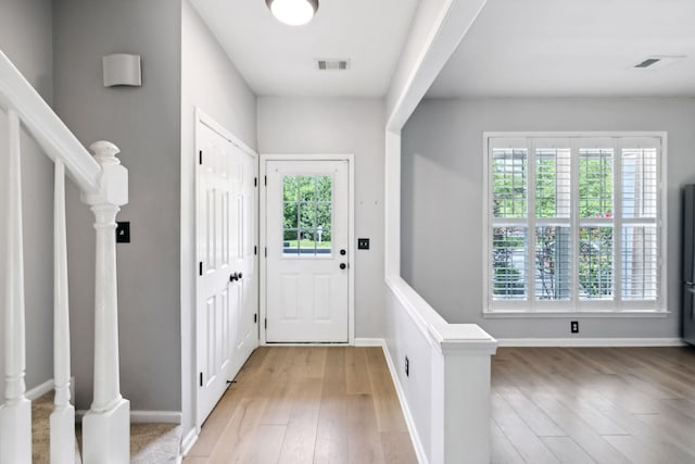 foyer with light wood-type flooring, stairway, and baseboards