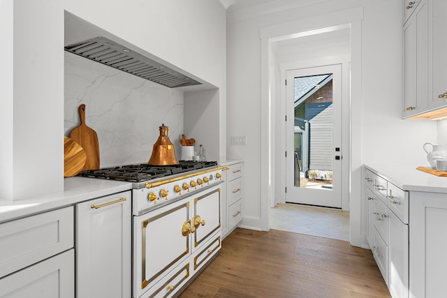 kitchen featuring range with two ovens, backsplash, healthy amount of natural light, and light wood finished floors