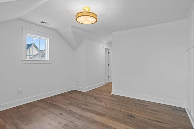 additional living space with vaulted ceiling, wood finished floors, and baseboards