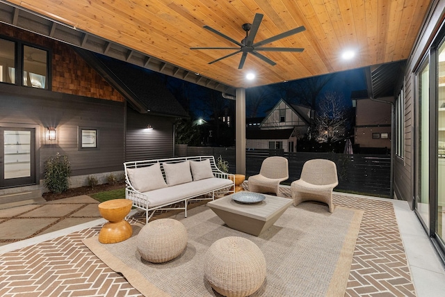 patio at night featuring outdoor lounge area, a ceiling fan, and fence