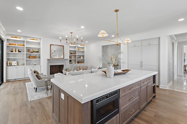 kitchen with black microwave, a chandelier, light wood finished floors, recessed lighting, and hanging light fixtures