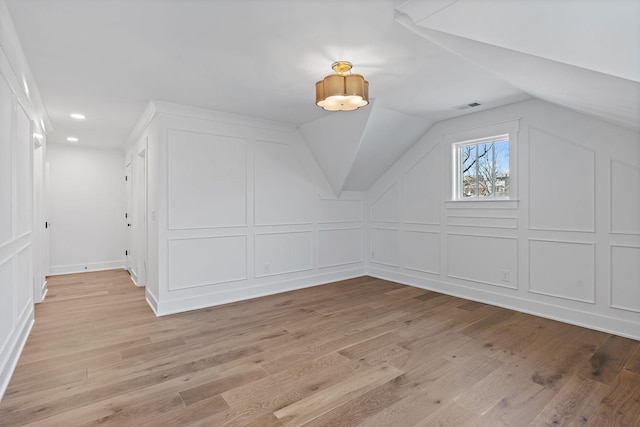 bonus room featuring a decorative wall, light wood-style flooring, lofted ceiling, and recessed lighting