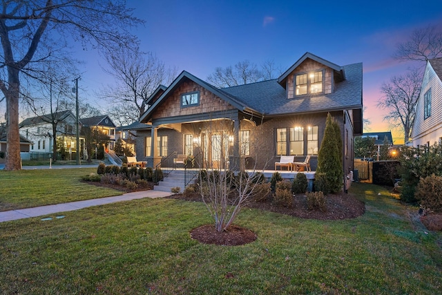 craftsman house with a porch, a front yard, and a shingled roof