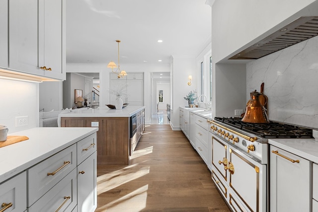 kitchen featuring tasteful backsplash, light countertops, wood finished floors, wall chimney exhaust hood, and recessed lighting