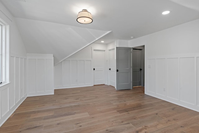 bonus room with a decorative wall, light wood finished floors, recessed lighting, and a wainscoted wall