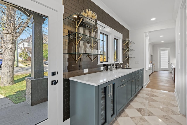 bar featuring wine cooler, ornamental molding, a sink, decorative backsplash, and baseboards