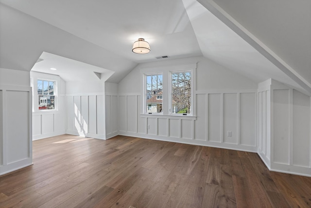 bonus room with a decorative wall, lofted ceiling, and hardwood / wood-style floors