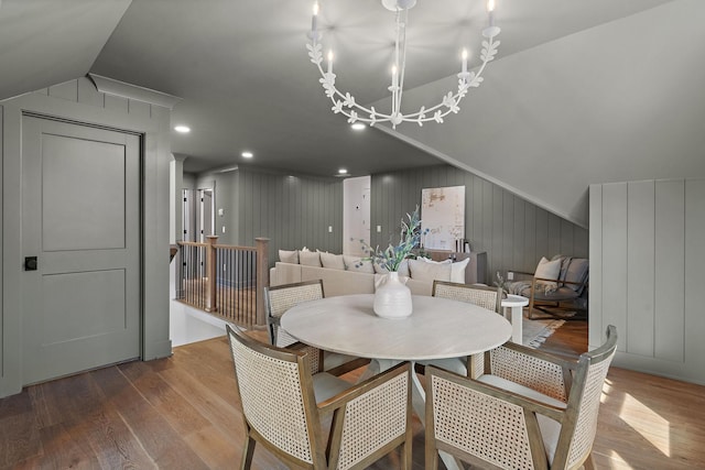 dining room featuring wood finished floors, lofted ceiling, and a chandelier