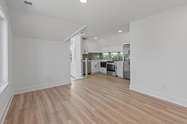 unfurnished living room with a sink, light wood-style floors, recessed lighting, and baseboards