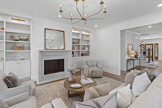 living room with a chandelier, baseboards, recessed lighting, light wood-style floors, and a premium fireplace