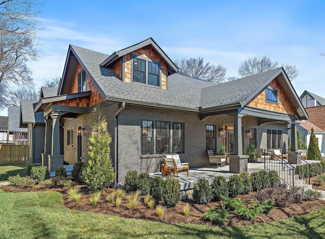 back of house featuring a shingled roof and brick siding