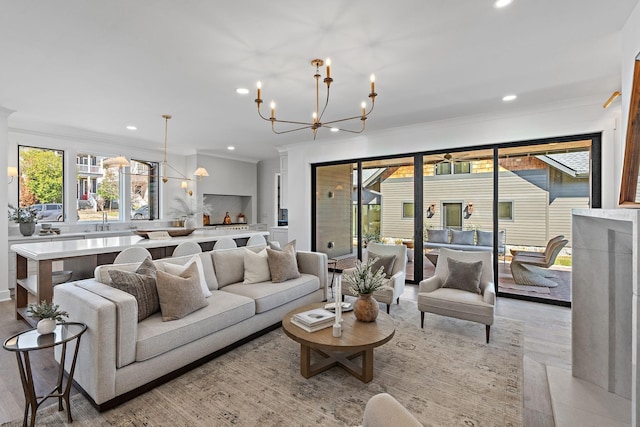 living area with a chandelier, ornamental molding, recessed lighting, and light wood-style flooring