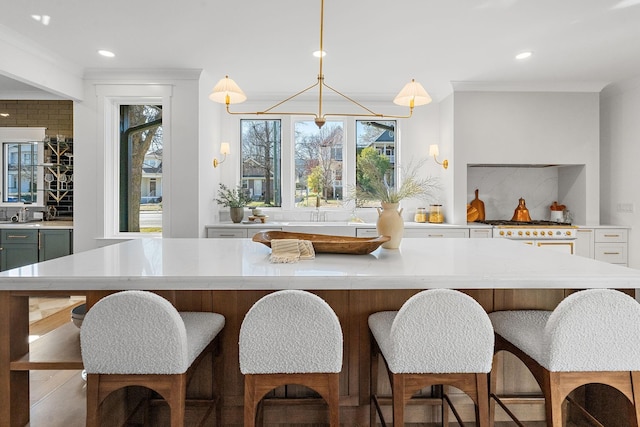 kitchen featuring light countertops, recessed lighting, a kitchen island, a sink, and a breakfast bar