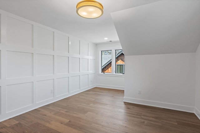 additional living space with wood finished floors, baseboards, and lofted ceiling